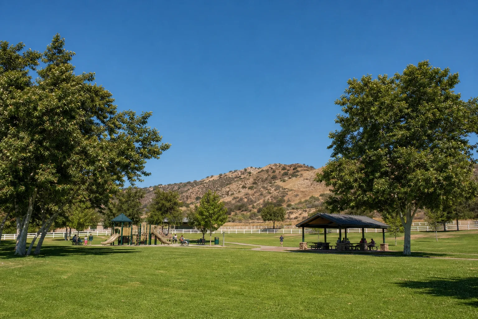 Green recreation lawn, playground, and picnic shelter representing Pikes Peak Park in Norco