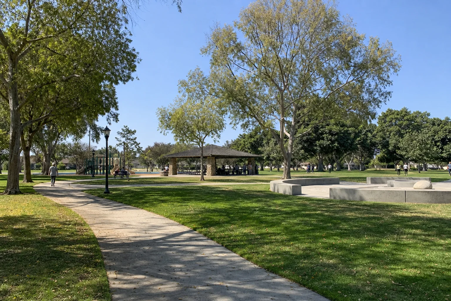 Tree-lined walking path, picnic pavilion, and green lawn representing Simms Park in Bellflower