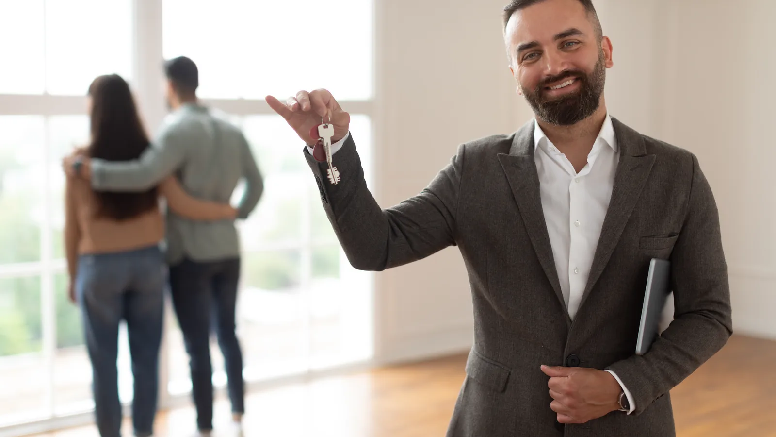 Real estate professional holding property keys inside a bright home