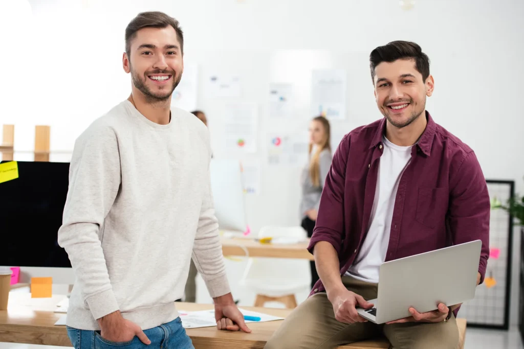 Two professionals working in a shared office with a laptop