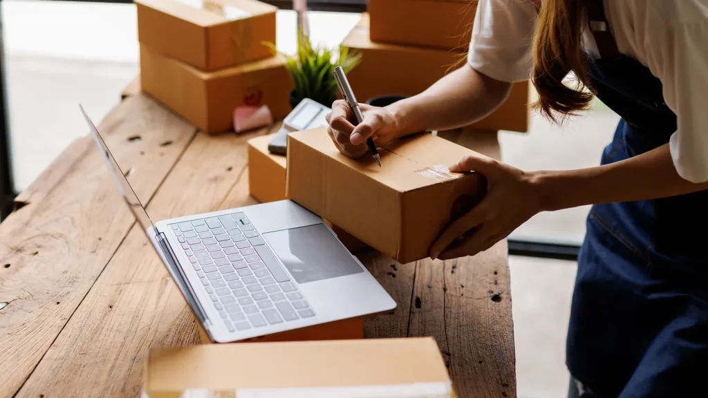Business owner preparing a package beside a laptop